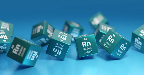 A group of 11 dice that all have the chemical symbol and number for radon, rolling on a blue surface. 